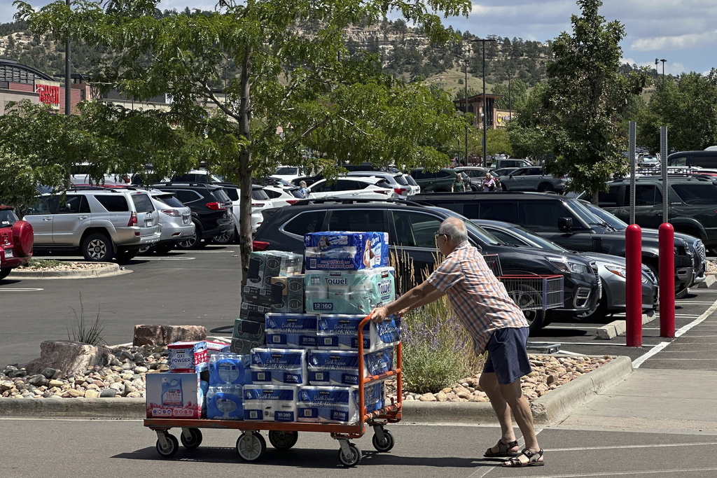 FILE - A shopper pushes a cart loaded with paper goods through the parking lot of a Costco warehouse Tuesday, Aug. 12, 2025, in Colorado springs, Colo. (AP Photo/David Zalubowski, File)