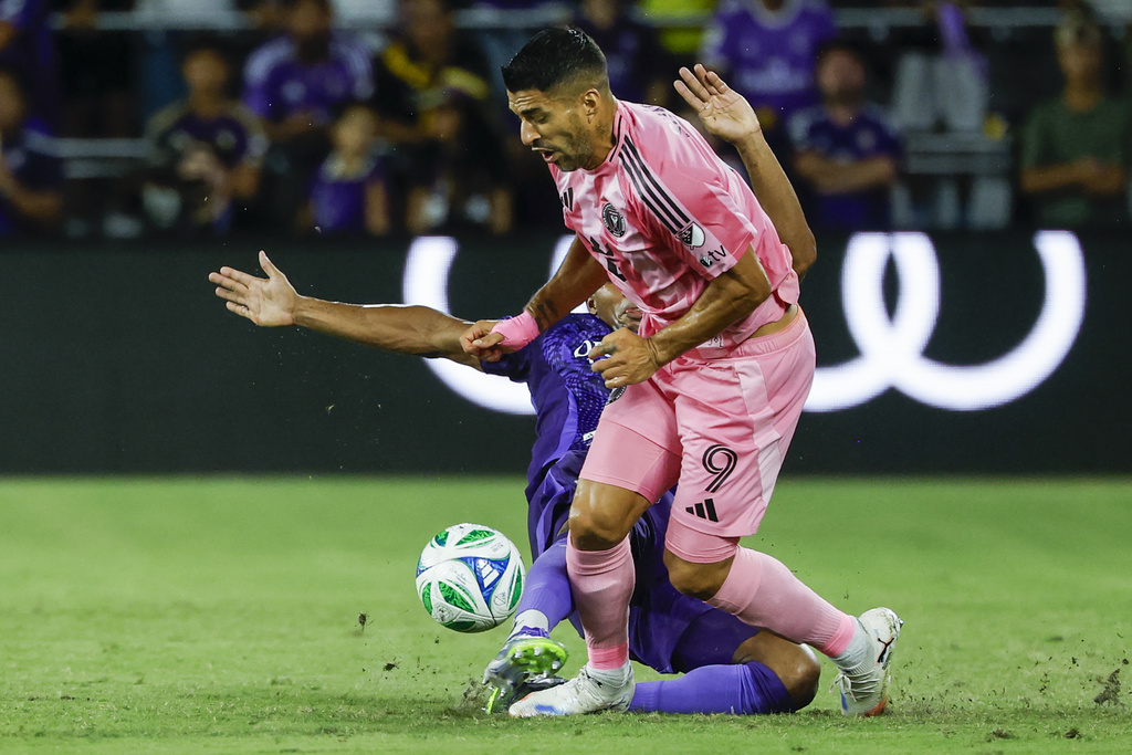 Orlando City defender Alex Freeman, left, slides into Inter Miami forward Luis Suárez (9) during the first half of an MLS soccer match, Sunday, Aug. 10, 2025, in Orlando, Fla. (AP Photo/Kevin Kolczynski)
