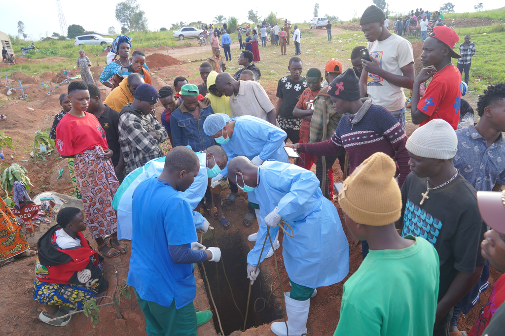 People dressed in protective gear lower into a grave the coffin containing the remains of 3-year-old Mave Mercienne, who died of Ebola, in Bunia, Ituri province, eastern Congo, Tuesday, Aug. 18, 2026. (AP Photo/Dieudonne Dirole)