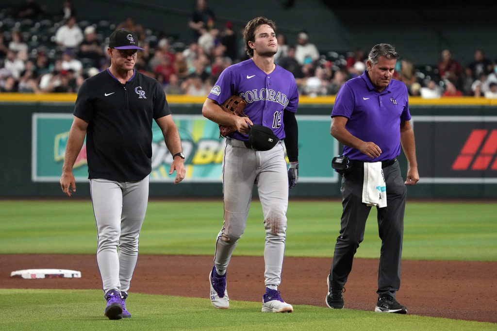 Colorado Rockies' Kyle Karros (12) leaves the game after colliding with Ezequiel Tovar on a ball hit by Arizona Diamondbacks' Ketel Marte in the sixth inning of a baseball game, Tuesday, Aug 11, 2026, in Phoenix. (AP Photo/Rick Scuteri)