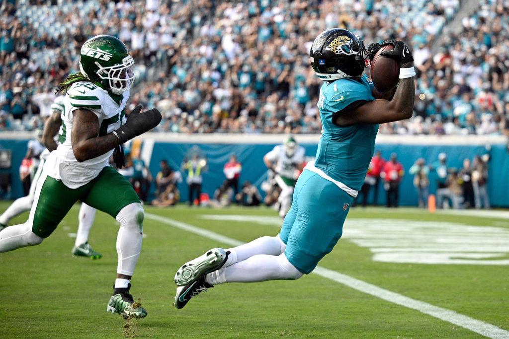 Jacksonville Jaguars running back Travis Etienne Jr. (1) makes a catch for a touchdown against New York Jets linebacker Quincy Williams (56) during the first half of an NFL football game, Sunday, Dec. 14, 2025, in Jacksonville, Fla. (AP Photo/Phelan M. Ebenhack)