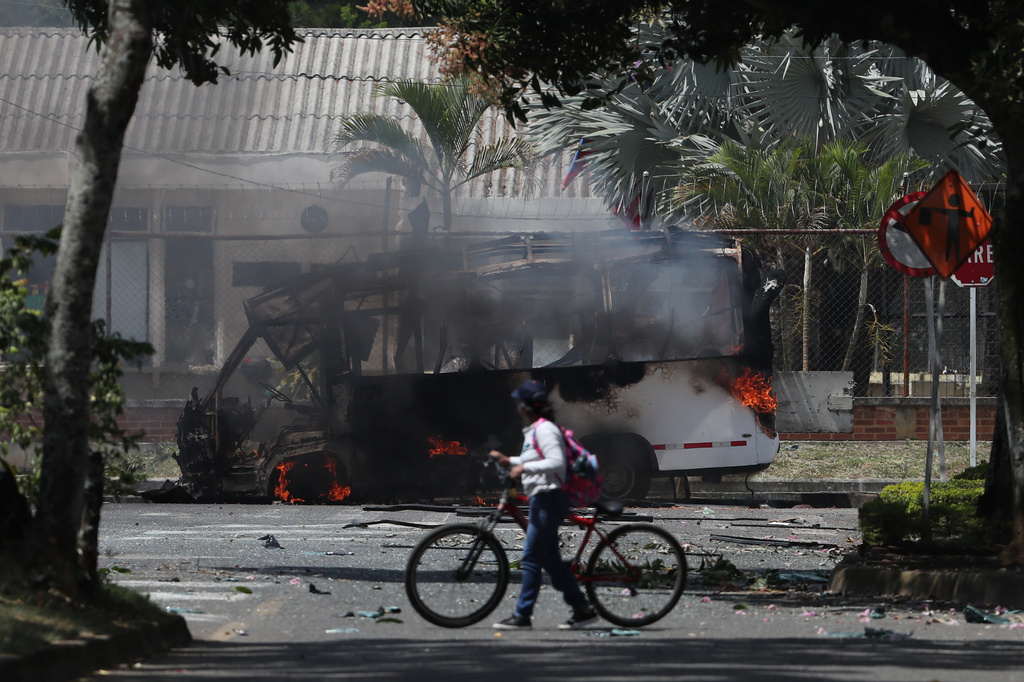 A bus burns after an explosion outside an army base in Cali, Colombia, Friday, April 24, 2026. (AP Photo/Santiago Saldariaga)