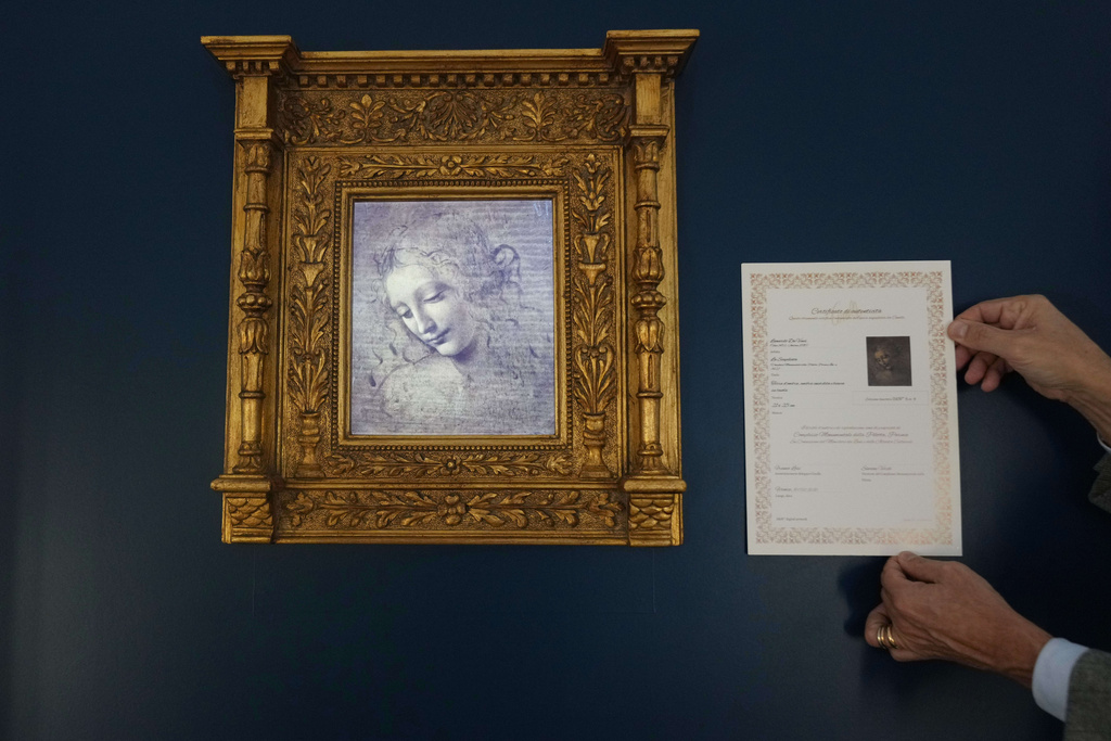 Primo Maronati holds a certificate next to a digital version of Leonardo Da Vinci's portrait, "La Scapiliata, Lady with Disheveled Hair," at the Brera Art Gallery in Milan, Italy, Monday, Nov. 24, 2025. (AP Photo/Antonio Calanni)