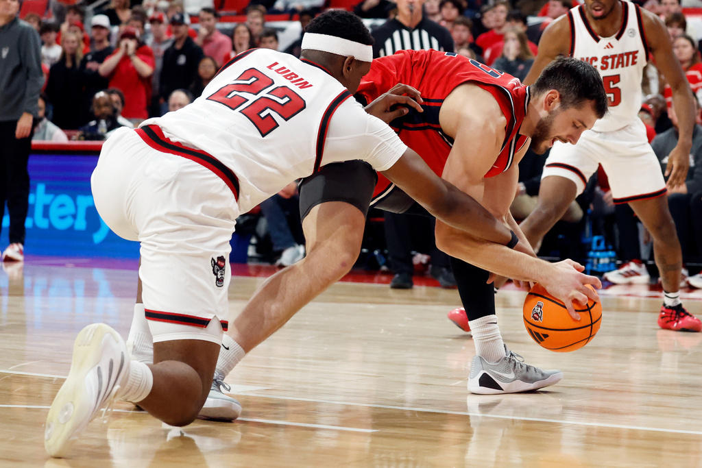 Liberty's Zach Cleveland, center, tries to regain control of the ball against North Carolina State's Ven-Allen Lubin (22) during the first half of an NCAA college basketball game in Raleigh, N.C., Wednesday, Dec. 10, 2025. (AP Photo/Karl DeBlaker)