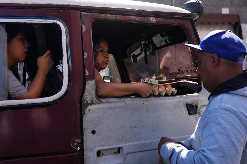 A woman buys eggs at a market in Caracas, Venezuela, Sunday, Jan. 4, 2026. (AP Photo/Ariana Cubillos)