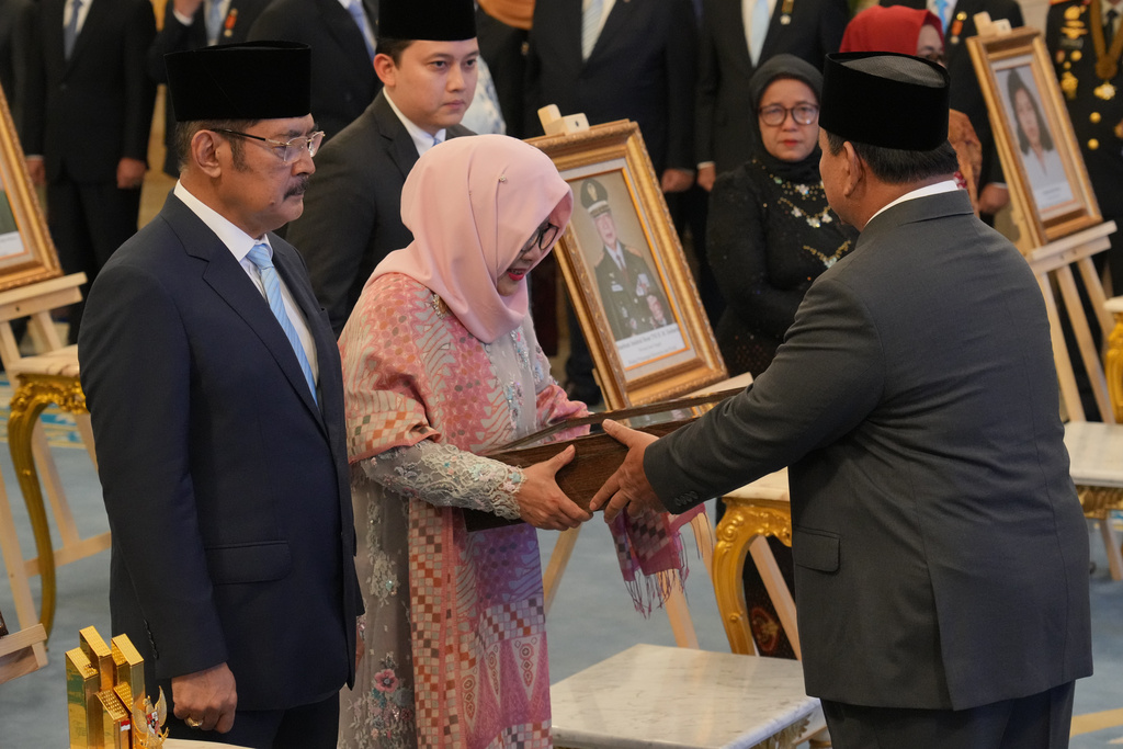 Indonesian President Prabowo Subianto, right, hands a national hero certificate to Siti Hardiyanti Rukmana, second left, daughter of the late President Suharto and son Bambang Trihatmojo, left, during a ceremony awarding national hero title to ten figures including the former strongman, at the State Palace in Jakarta, Indonesia, Monday, Nov. 10, 2025. (AP Photo/Achmad Ibrahim)