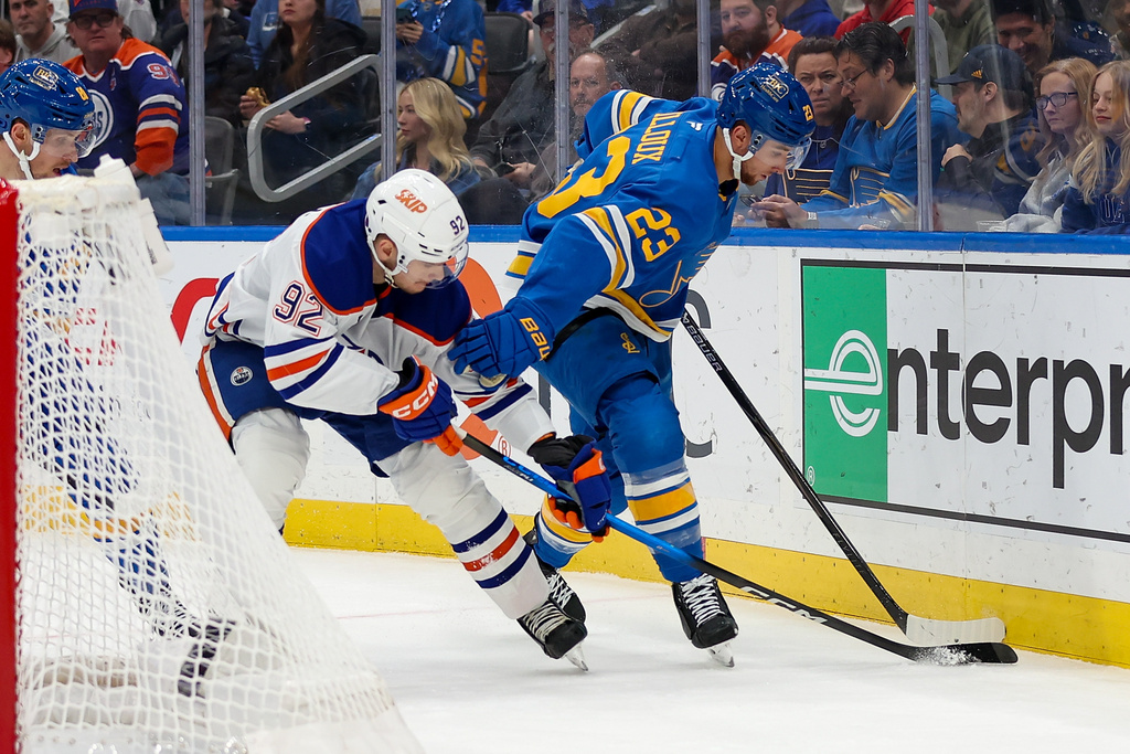 St. Louis Blues' Logan Mailloux (23) and Edmonton Oilers' Vasily Podkolzin (92) battle for control of the puckduring the first period of an NHL hockey game Friday, March 13, 2026, in St. Louis. (AP Photo/Scott Kane)