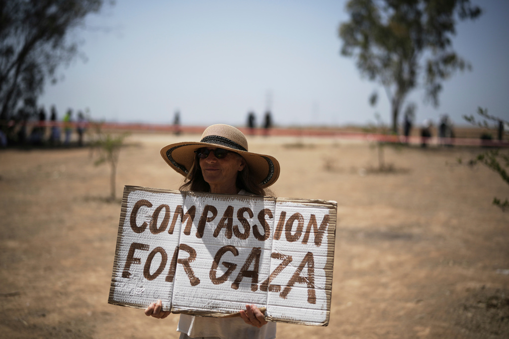 A woman holds a sign as peace activists march to call for an end to the war and starvation of civilians and the release of all hostages held by Hamas in the Gaza Strip, near the Israel-Gaza border in southern Israel, Friday, June 6, 2025. (AP Photo/Leo Correa)