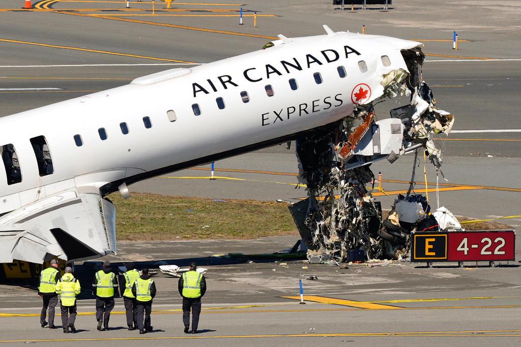 Aircraft maintenance workers arrive to inspect the wreckage of an Air Canada Express jet, Tuesday, March 24, 2026, just off the runway where it had collided with a Port Authority fire truck Sunday night at LaGuardia Airport in New York. (AP Photo/Yuki Iwamura)