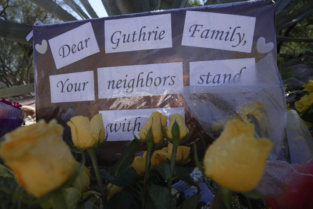 Yellow flowers and signs remain at a vigil outside of Nancy Guthrie’s home on Saturday, Feb. 14, 2026 in Tucson, Ariz. (AP Photo/Ty O'Neil)