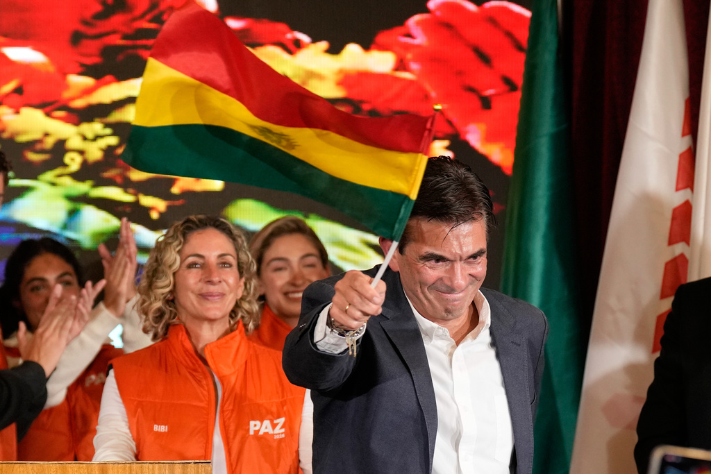 Presidential candidate Rodrigo Paz waves a Bolivian flag after preliminary results showed him leading in the presidential runoff election in La Paz, Bolivia, Sunday, Oct. 19, 2025. (AP Photo/Natacha Pisarenko)