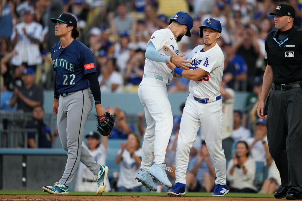 Los Angeles Dodgers' Andy Pages, second from left, collides with Tommy Edman, second from right, as he scores on a double by Mookie Betts as Seattle Mariners starting pitcher Bryan Woo walks away during the first inning of a baseball game Thursday, July 30, 2026, in Los Angeles. (AP Photo/Mark J. Terrill)