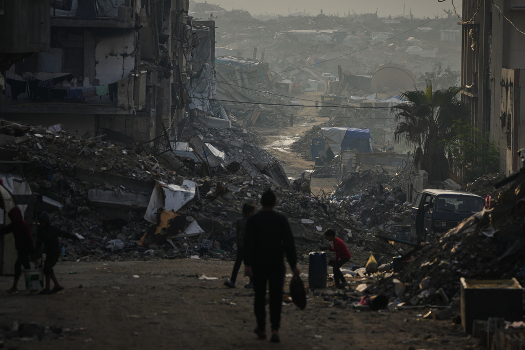 Palestinians walk through the destruction left by the Israeli air and ground offensive in Gaza City, Saturday, Nov. 29, 2025. (AP Photo/Abdel Kareem Hana)