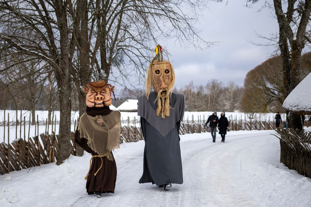 Revellers wearing traditional carnival masks take part in Shrovetide celebrations in the village of Rumsiskes, some 89 kilometers (56 miles) north of Vilnius, Lithuania, Saturday, Feb. 14, 2026. (AP Photo/Mindaugas Kulbis)