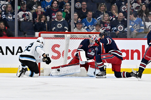 Winnipeg Jets goaltender Connor Hellebuyck (37) makes a save against Utah Mammoth's Jack McBain (22) during the second period of an NHL hockey game in Winnipeg, Manitoba, Sunday, Oct. 26, 2025. (Fred Greenslade/The Canadian Press via AP) Winnipeg Jets goaltender Connor Hellebuyck (37) makes a save against Utah Mammoth's Jack McBain (22) during the second period of an NHL hockey game in Winnipeg, Manitoba, Sunday, Oct. 26, 2025. (Fred Greenslade/The Canadian Press via AP)