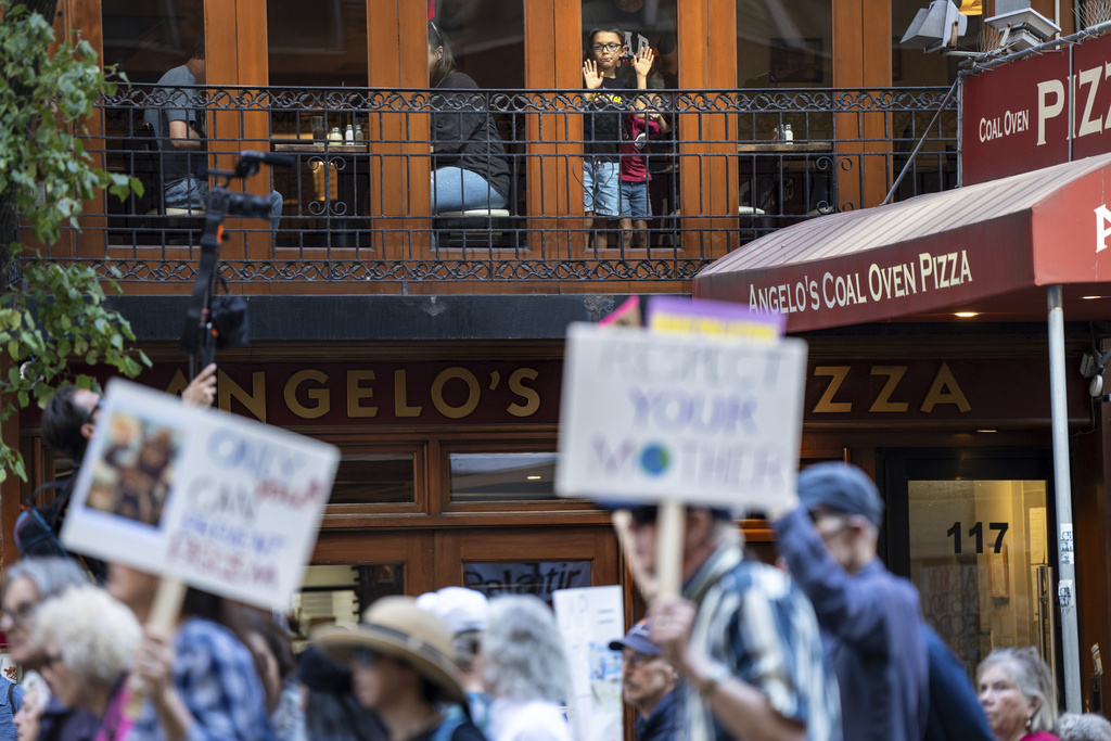 Children watch from inside a restaurant as people march through Manhattan in the "Make Billionaires Pay" climate protest in New York, Saturday, Sept. 20, 2025. (AP Photo/Angelina Katsanis)