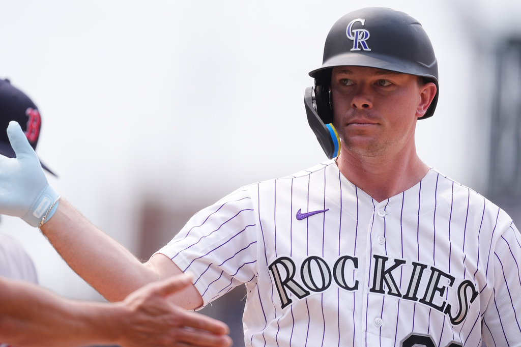 Colorado Rockies pinch-hitter Troy Johnston is congratulated after his RBI single of Boston Red Sox relief pitcher Danny Coulombe in the seventh inning of a baseball game Wednesday, June 24, 2026, in Denver. (AP Photo/David Zalubowski)