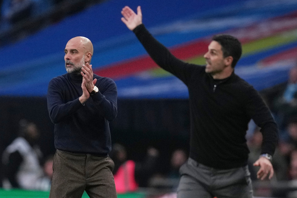 Manchester City's head coach Pep Guardiola, left encourages his players as Arsenal's manager Mikel Arteta gestures to his during the English League Cup final soccer match between Arsenal and Manchester City in London, Sunday, March 22, 2026. (AP Photo/Maja Smiejkowska)