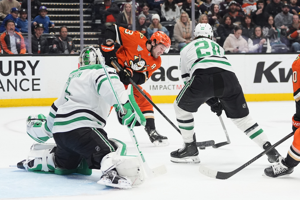 Anaheim Ducks center Mason McTavish, center, shoots as Dallas Stars goaltender Casey DeSmith, left, and defenseman Alexander Petrovic defend during the first period of an NHL hockey game Tuesday, Jan. 13, 2026, in Anaheim, Calif. (AP Photo/Gregory Bull)