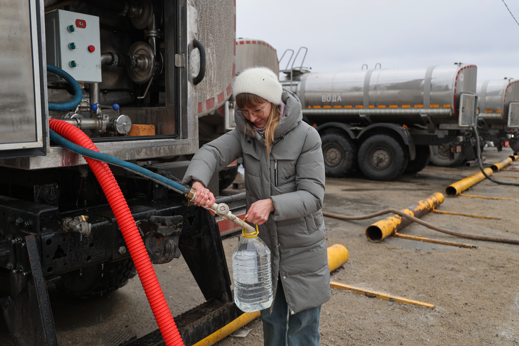 A woman gets drinking water distributed by authorities in the city of Donetsk in the Russian-controlled part of eastern Ukraine, on Thursday, Feb. 19, 2026. (AP Photo)