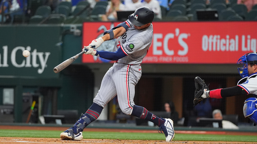 Minnesota Twins' Brooks Lee, left, hits a home run in front of Texas Rangers catcher Kyle Higashioka during the first inning of a baseball game against the Texas Rangers, Thursday, June 18, 2026, in Arlington, Texas. (AP Photo/LM Otero)