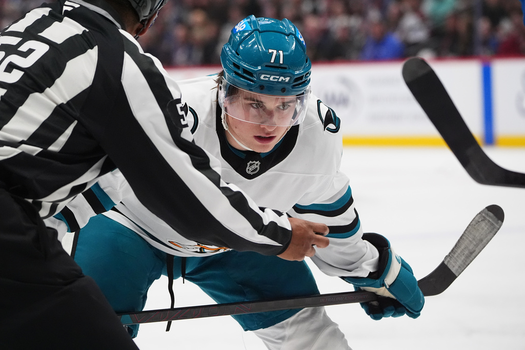 San Jose Sharks center Macklin Celebrini, back, waits for linesman Shandor Alphonso to drop the puck while facing off against Colorado Avalanche center Nathan MacKinnon in the second period of an NHL hockey game Wednesday, Nov. 26, 2025, in Denver. (AP Photo/David Zalubowski)
