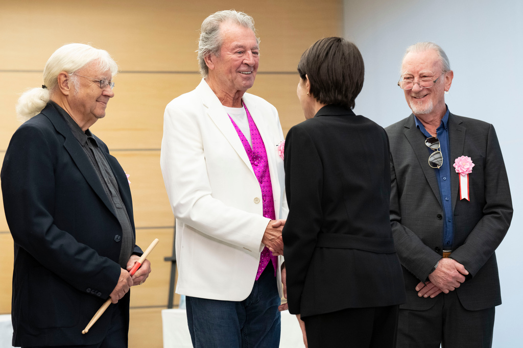 Japan's Prime Minister Sanae Takaichi, back to camera, greets members of British rock band Deep Purple , from left, Ian Paice, Ian Gillan, and Roger Glover at the Prime Minister's Office in Tokyo, Friday, April 10, 2026. (Yuichi Yamazaki/Pool Photo via AP)