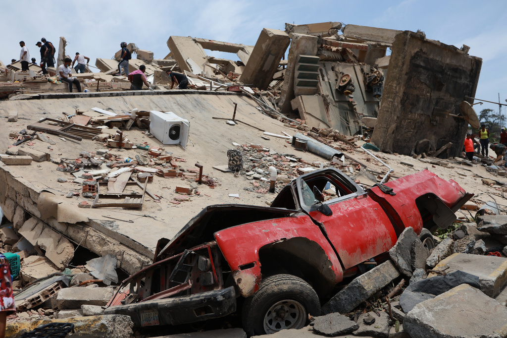 A vehicle is crushed at a building that collapsed after earthquakes struck La Guaira, Venezuela, Thursday, June 25, 2026. (AP Photo/Javier Campos)