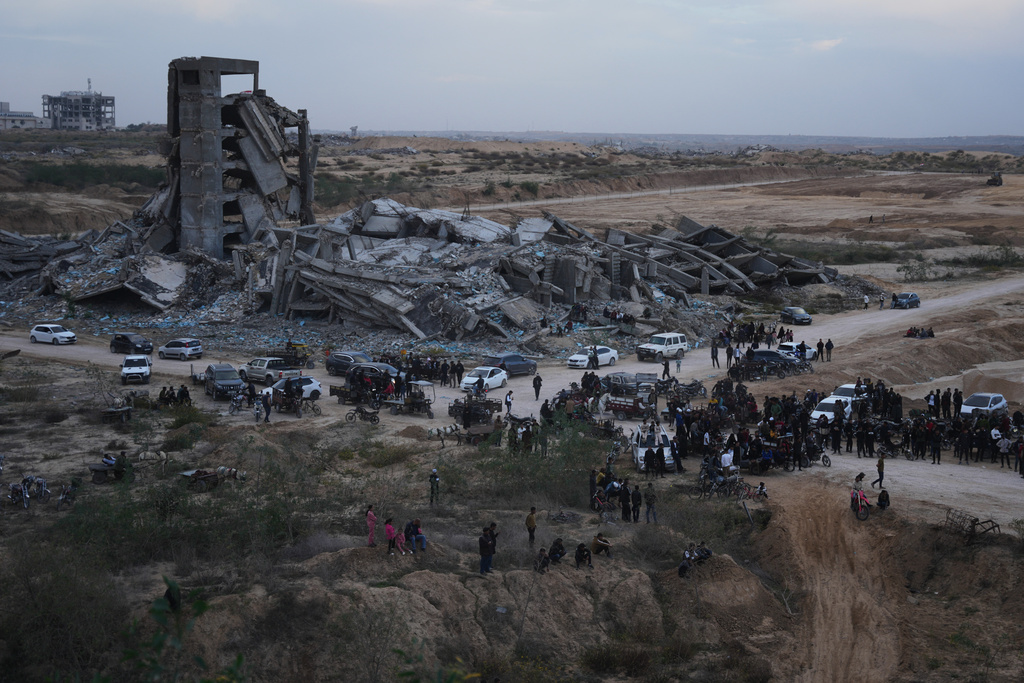 Palestinians watch youths riding their motorcycles on sand dunes in the Al-Zahra area, in the central Gaza Strip, Friday, Dec. 5, 2025. (AP Photo/Abdel Kareem Hana)