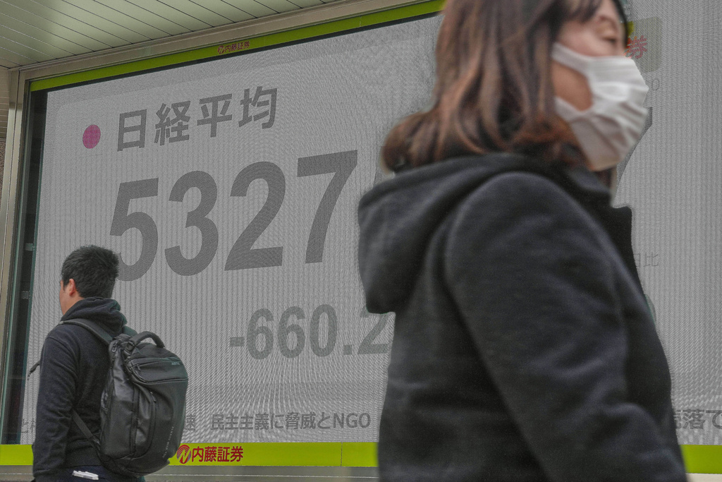 People walk in front of an electronic stock board showing Japan's Nikkei index at a securities firm Monday, Jan. 19, 2026, in Tokyo. (AP Photo/Eugene Hoshiko)