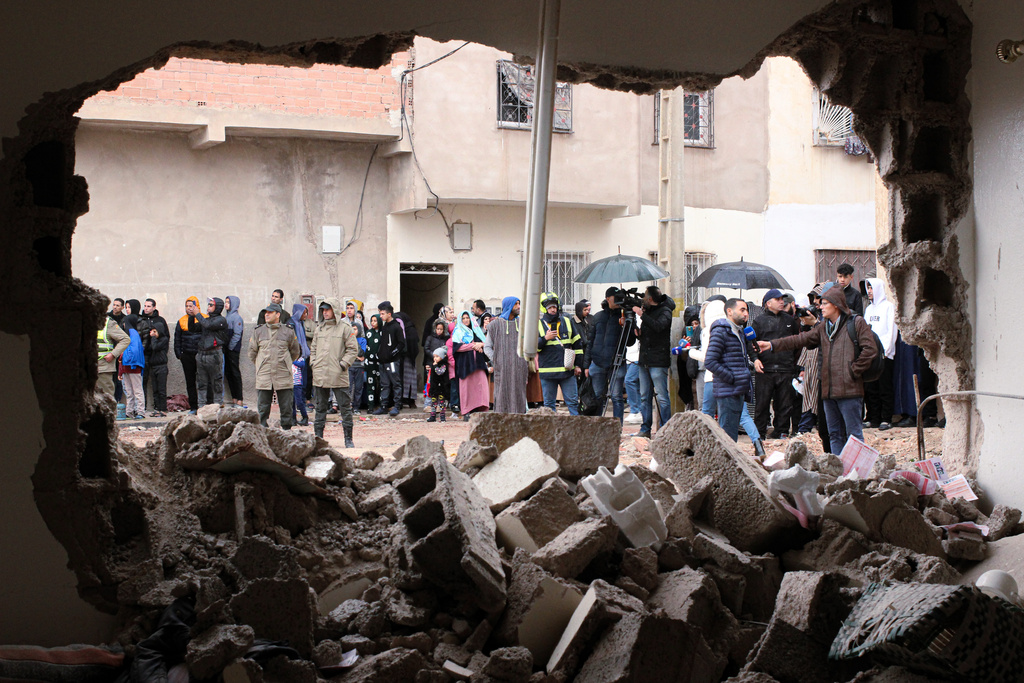 Residents and jounalists watch as rescue workers search for survivors, amid the wreckage of two collapsed buildings, in Fez, Morocco, Wednesday, Dec. 10, 2025. (AP Photo/Hanane Boukili)