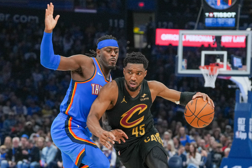 Cleveland Cavaliers guard Donovan Mitchell, right, drives past Oklahoma City Thunder guard Luguentz Dort, left, during the second half of an NBA basketball game, Sunday, Feb. 22, 2026, in Oklahoma City. (AP Photo/Kyle Phillips)