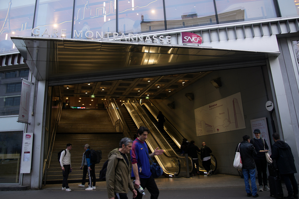 People walk past the Montparnasse train station after a man wielding a knife at the station was shot and wounded by police, Friday, Nov. 14, 2025 in Paris. (AP Photo/Christophe Ena)