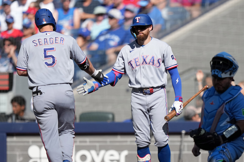 Texas Rangers' Corey Seager (5) celebrates after his solo home run with teammate Brandon Nimmo, second from left, during the sixth inning of a baseball game against the Toronto Blue Jays in Toronto, Saturday, June 27, 2026. (Nathan Denette/The Canadian Press via AP)