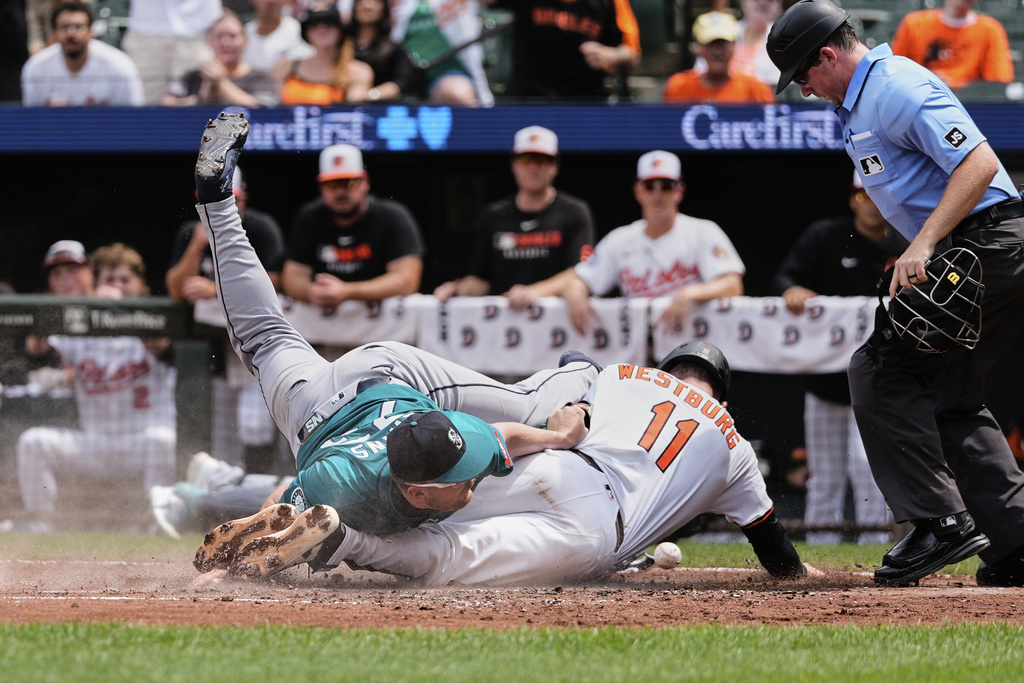 Baltimore Orioles' Jordan Westburg (11) scores past Seattle Mariners starting pitcher Logan Evans, left, on a wild pitch and fielding error by Evans during the fourth inning of a baseball game, Thursday, Aug. 14, 2025, in Baltimore. (AP Photo/Stephanie Scarbrough)