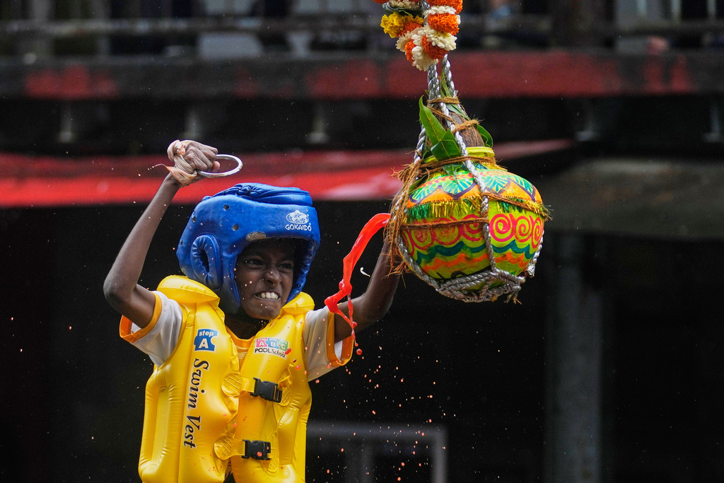 Curd spills as a boy tries to break an earthen pot filled with curd, after climbing on top of a human pyramid as part of celebrations to mark Janmashtami festival in Mumbai, India, Saturday, Aug. 16, 2025. (AP Photo/Rajanish Kakade)