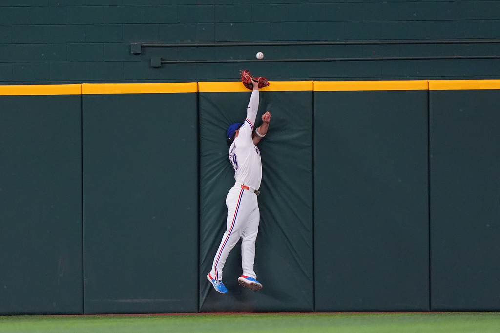 Texas Rangers center fielder Alejandro Osuna can't reach the home run ball at the wall hit by Minnesota Twins' Trevor Larnach during the fourth inning of a baseball game, Thursday, June 18, 2026, in Arlington, Texas. (AP Photo/LM Otero)