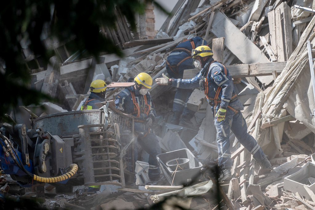 Emergency services from the Federal Agency for Technical Relief (THW) use their bare hands to remove the mountain of rubble from the collapsed residential building in the city center of Goerlitz, Germany, Tuesday, May 19, 2026. (Paul Glaser/dpa via AP)