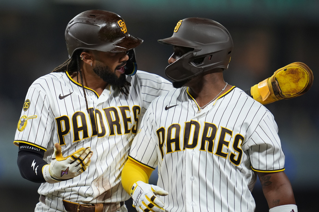 San Diego Padres' baserunners Fernando Tatis Jr., left, and Miguel Andujar chat as the Los Angeles Dodgers change pitchers during the seventh inning of a baseball game Tuesday, May 19, 2026, in San Diego. (AP Photo/Gregory Bull)
