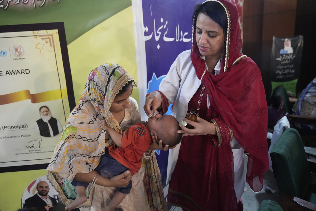 A doctor, right, gives medicine to a child at a relief camp set up for people who fled their homes following torrential rains and rising water level in the Ravi river, on the outskirts of in Lahore, Pakistan, Sunday, Aug. 31, 2025. (AP Photo/K.M. Chaudary)