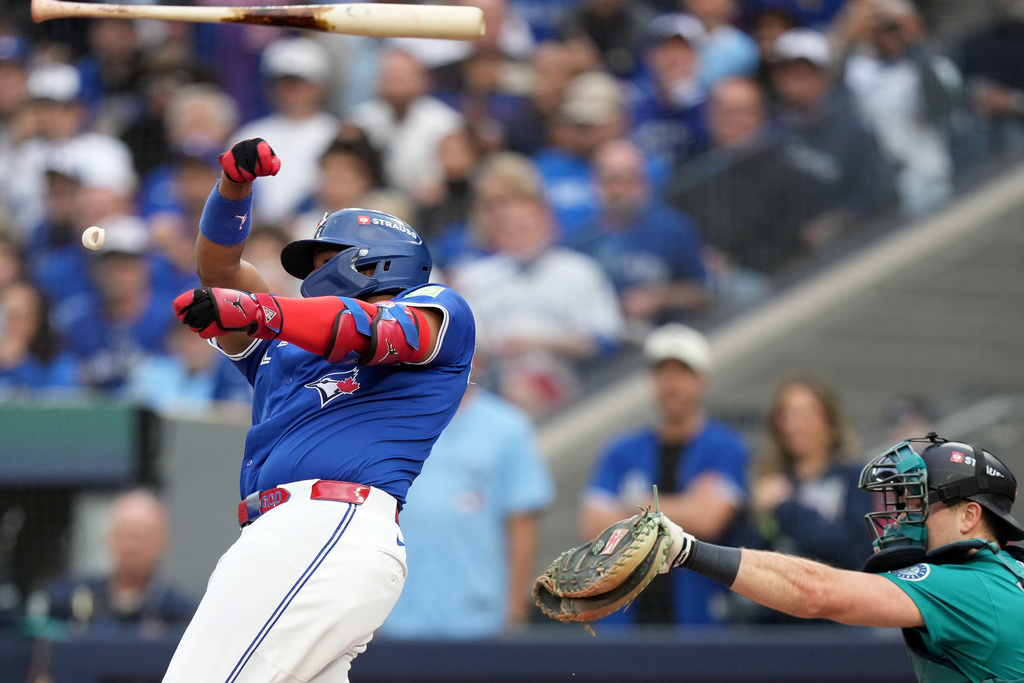 Toronto Blue Jays' Vladimir Guerrero Jr., left, loses his bat during a swing during the first inning of Game 2 of baseball's American League Division Series against the Seattle Mariners in Toronto, Monday, Oct. 13, 2025. (Nathan Denette/The Canadian Press via AP)