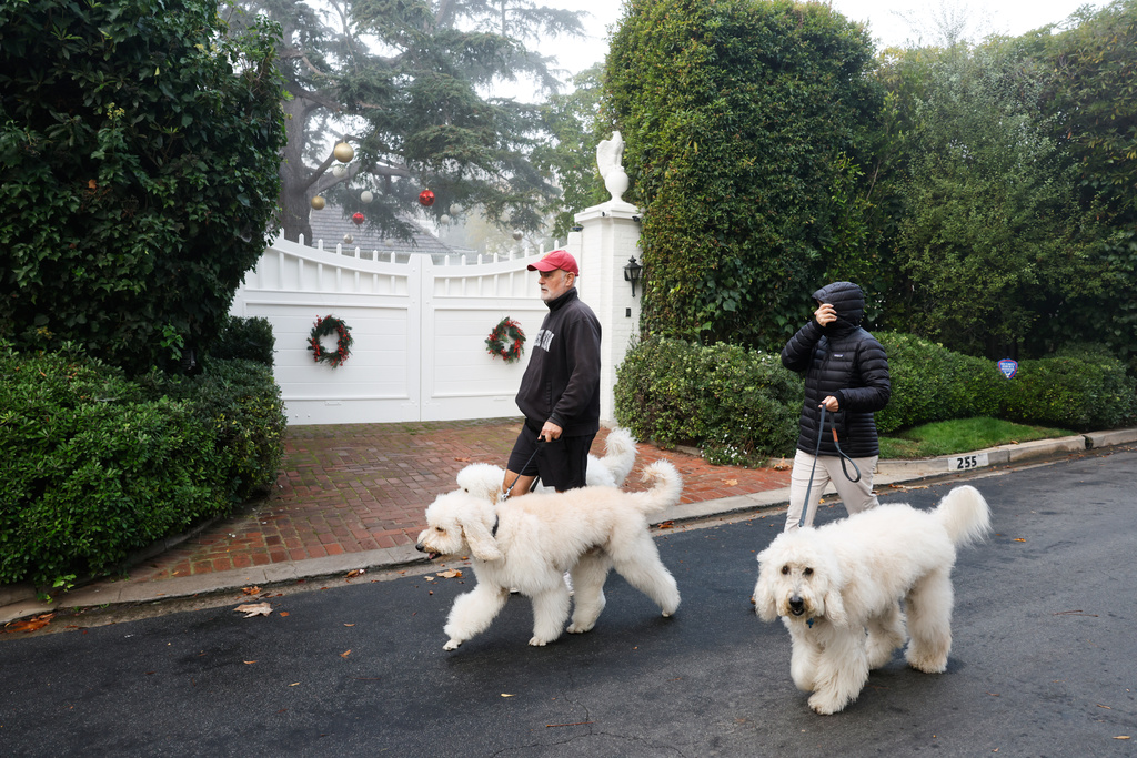 People walk dogs past Rob Reiner's residence, Monday, Dec. 15, 2025, in the Brentwood section of Los Angeles. (AP Photo/Caroline Brehman)