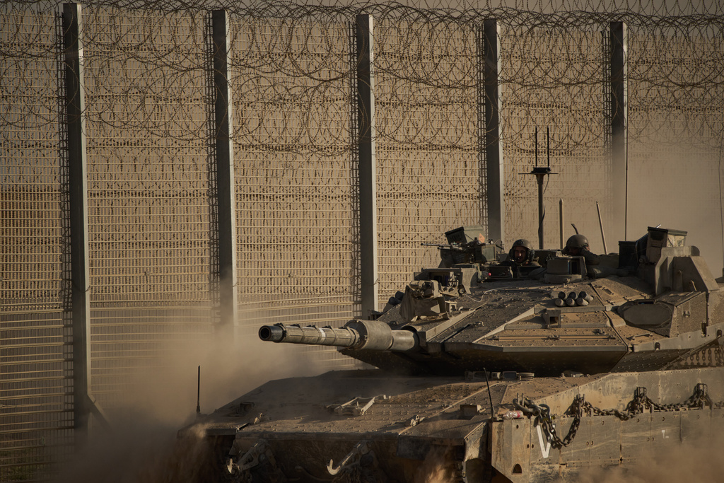Israeli soldiers move on top of a tank along the Israeli-Gaza border as seen from southern Israel, Tuesday, Oct. 21, 2025. (AP Photo/Leo Correa)