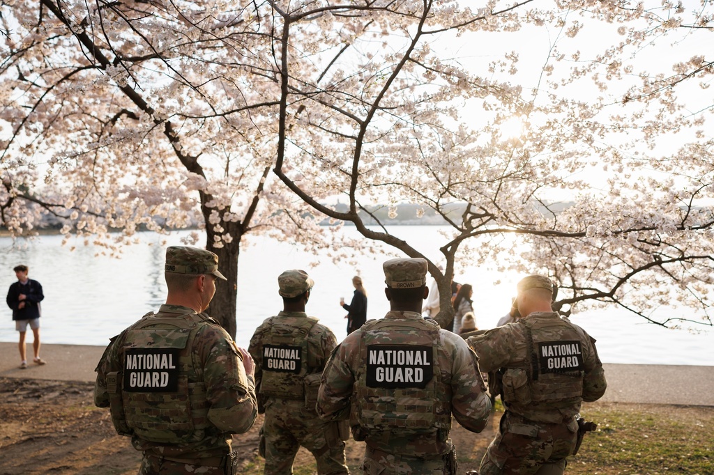 Members of the Mississippi National Gard patrol among the cherry blossom trees along the tidal basin on the National Mall on Thursday, March 26, 2026, in Washington. (AP Photo/Tom Brenner)