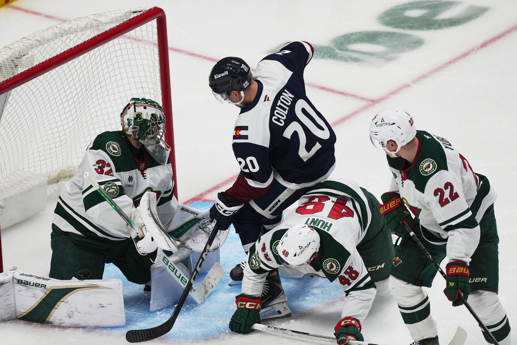 Colorado Avalanche center Ross Colton, second from left, puts a shot on Minnesota Wild goaltender Filip Gustavsson, left, after driving past defenseman Daemon Hunt, third form left, and right wing Danila Yurov in the third period of an NHL hockey game Thursday, Feb. 26, 2026, in Denver. (AP Photo/David Zalubowski)
