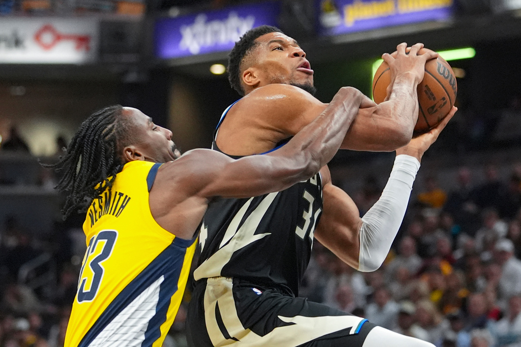 Indiana Pacers guard/forward Aaron Nesmith (23) fouls Milwaukee Bucks forward Giannis Antetokounmpo (34) during the first half of an NBA basketball game in Indianapolis, Monday, Nov. 3, 2025. (AP Photo/Michael Conroy)