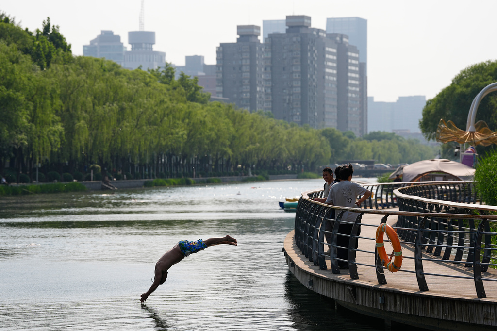 People watch a man jump into the Liangmahe river, in Beijing, Tuesday, May 12, 2026. (AP Photo/Andy Wong)