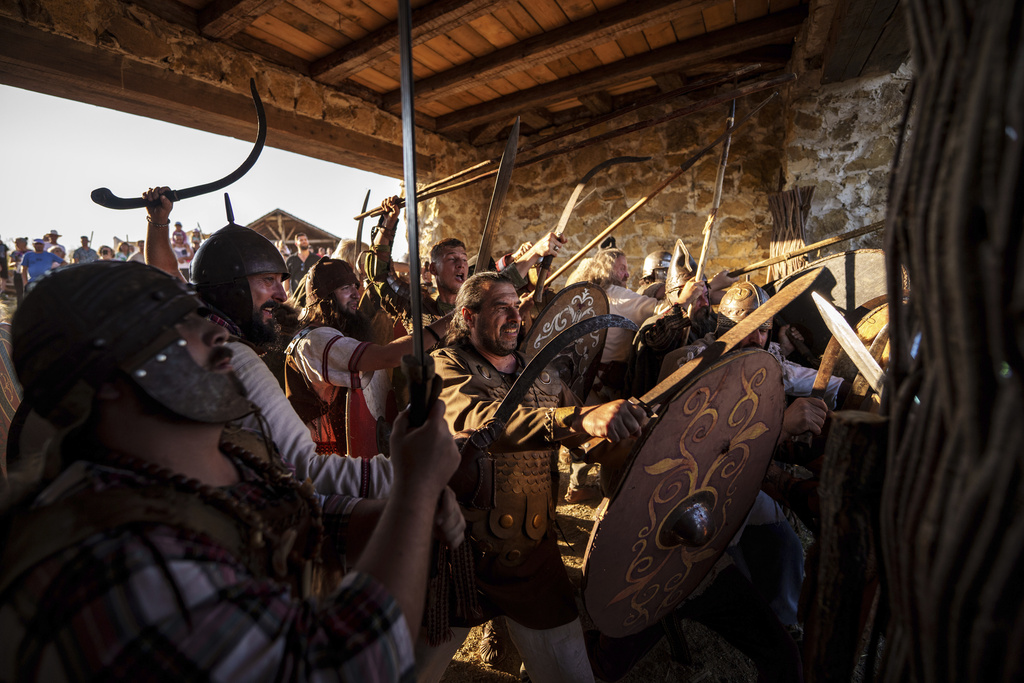 Members of historical reenactment groups wearing Dacian warrior outfits, try to repel an attack by Roman empire soldiers in Poiana, Romania, Sunday, July 13, 2025, during the Getodava historical reenactment festival. (AP Photo/Vadim Ghirda)