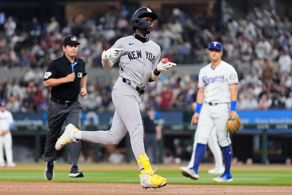 New York Yankees' Jazz Chisholm Jr. celebrates his solo home run in the fourth inning of a baseball game as umpire Ben May and Texas Rangers third baseman Josh Jung, right rear, look on Monday, April 27, 2026, in Arlington, Texas. (AP Photo/Tony Gutierrez)