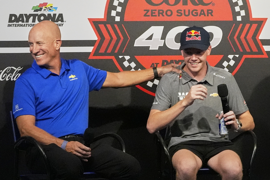 Dr. Eric Warren, left, vice president of global motorsports competition of General Motors, jokes with driver Connor Zilisch during an auto racing news conference at Daytona International Speedway, Saturday, Aug. 23, 2025, in Daytona Beach, Fla. (AP Photo/John Raoux)